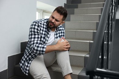 Photo of Man fallen down stairs suffering from pain in knee indoors
