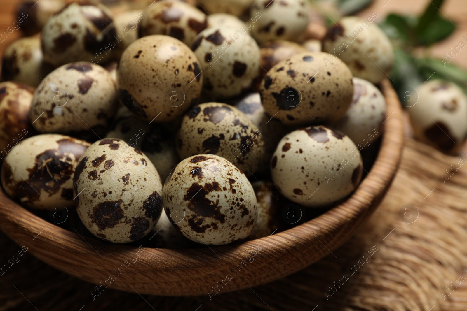 Photo of Wooden bowl with quail eggs on table, closeup