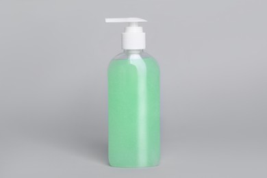 Bottle of face cleansing product on light grey background. Space for text