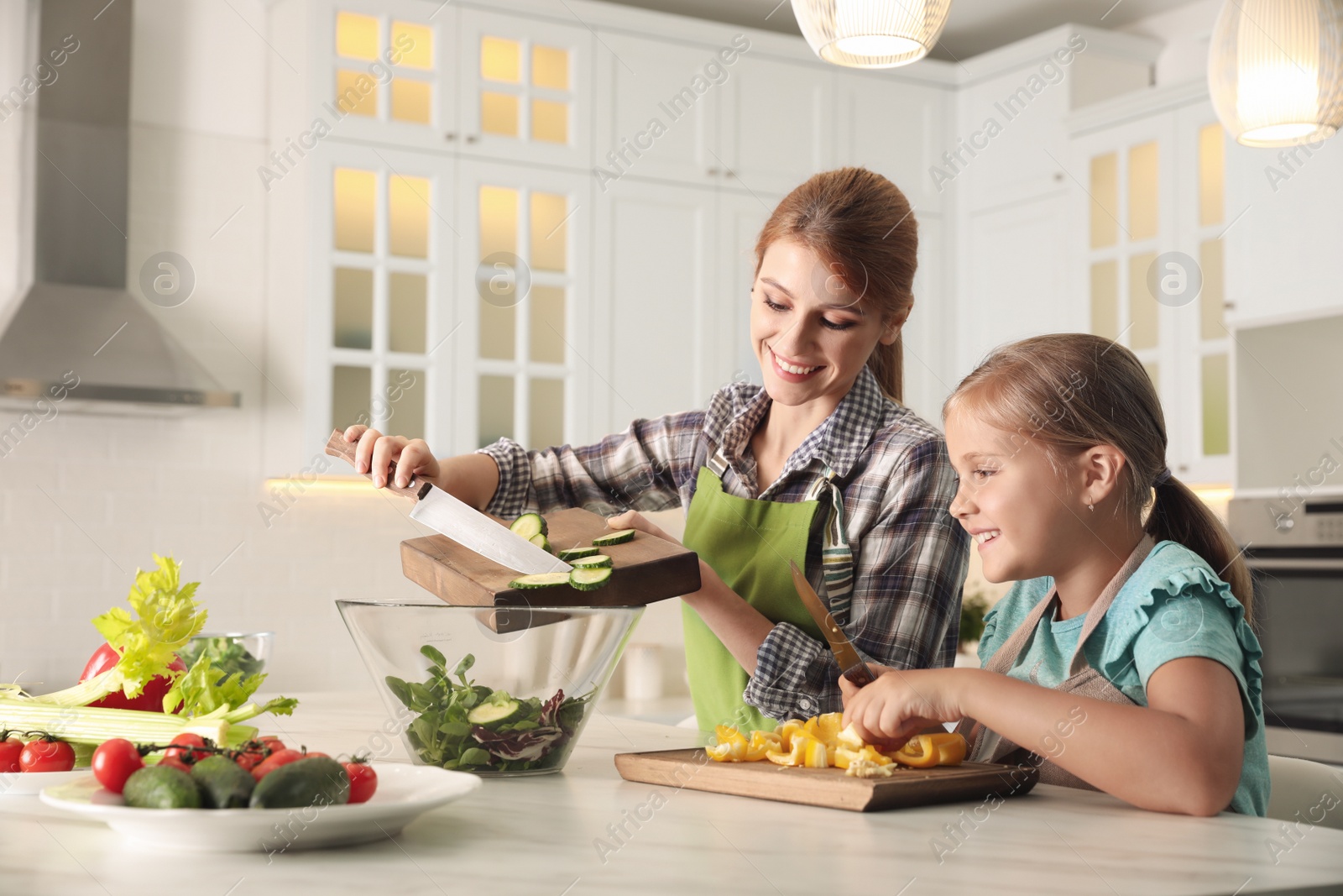 Photo of Mother and daughter cooking salad together in kitchen