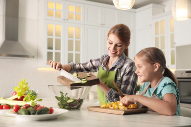 Mother and daughter cooking salad together in kitchen