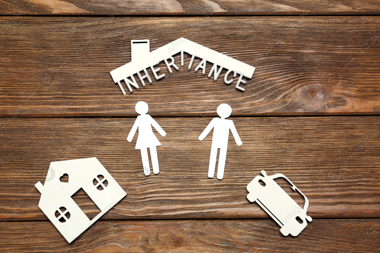 Photo of Word Inheritance made with white letters and different cutouts on wooden table, flat lay