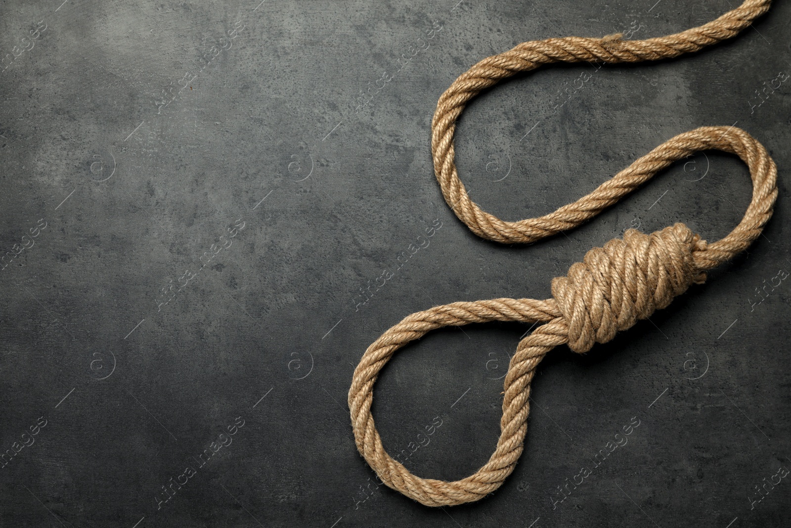 Photo of Rope noose with knot on grey table, top view. Space for text