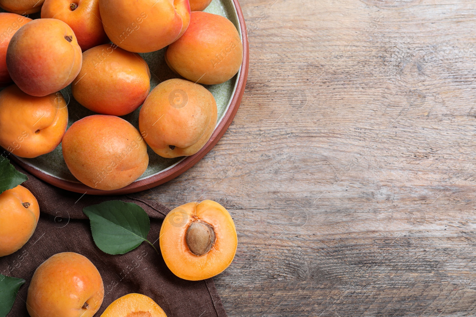 Photo of Delicious fresh ripe apricots on wooden table, flat lay. Space for text