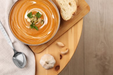 Photo of Delicious pumpkin soup served on wooden table, flat lay. Space for text