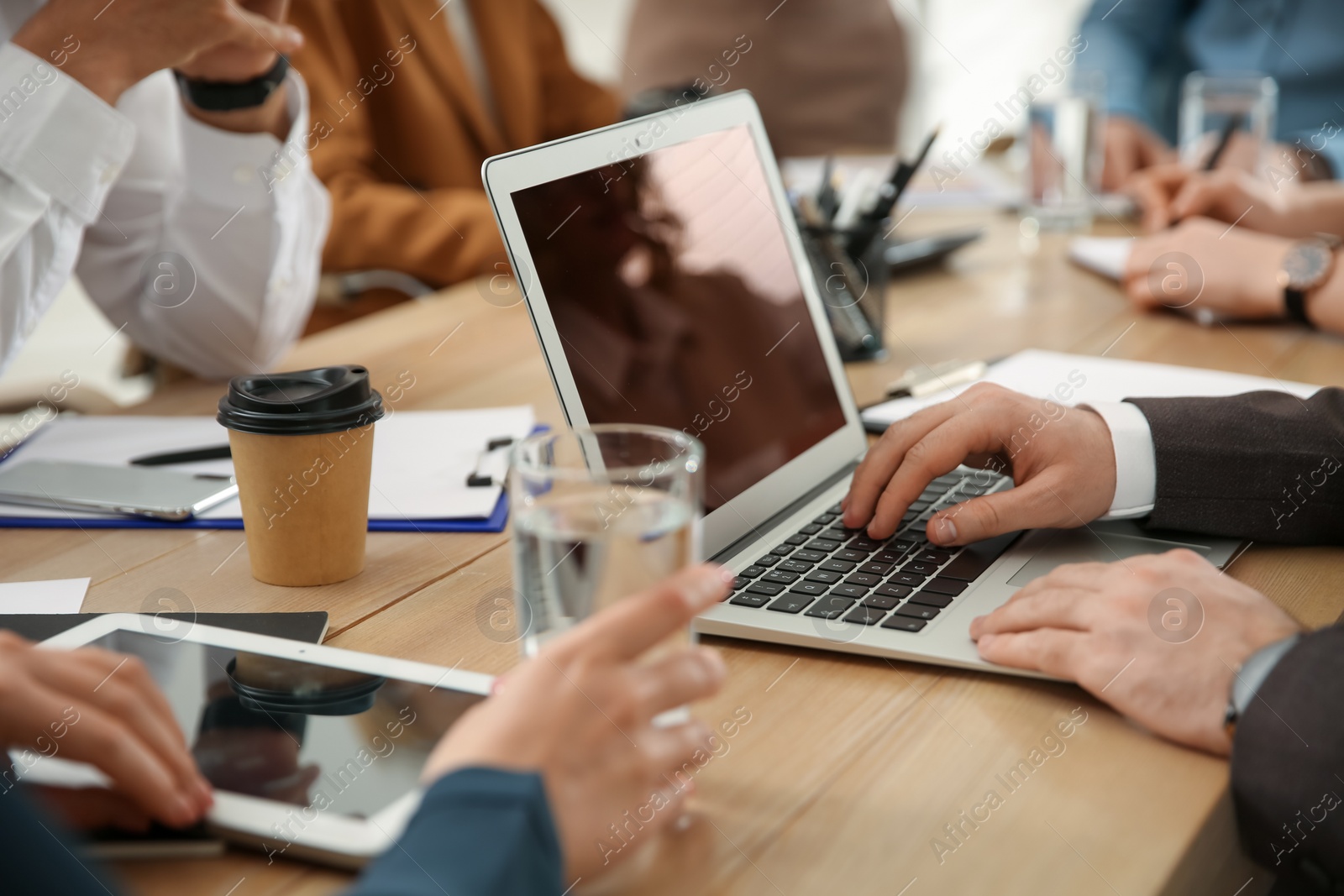 Photo of Man using laptop at table in office during business meeting, closeup. Management consulting