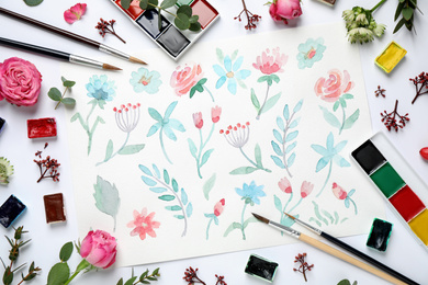 Flat lay composition with watercolor paints and floral picture on white background