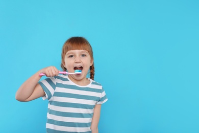 Little girl brushing teeth on color background. Space for text