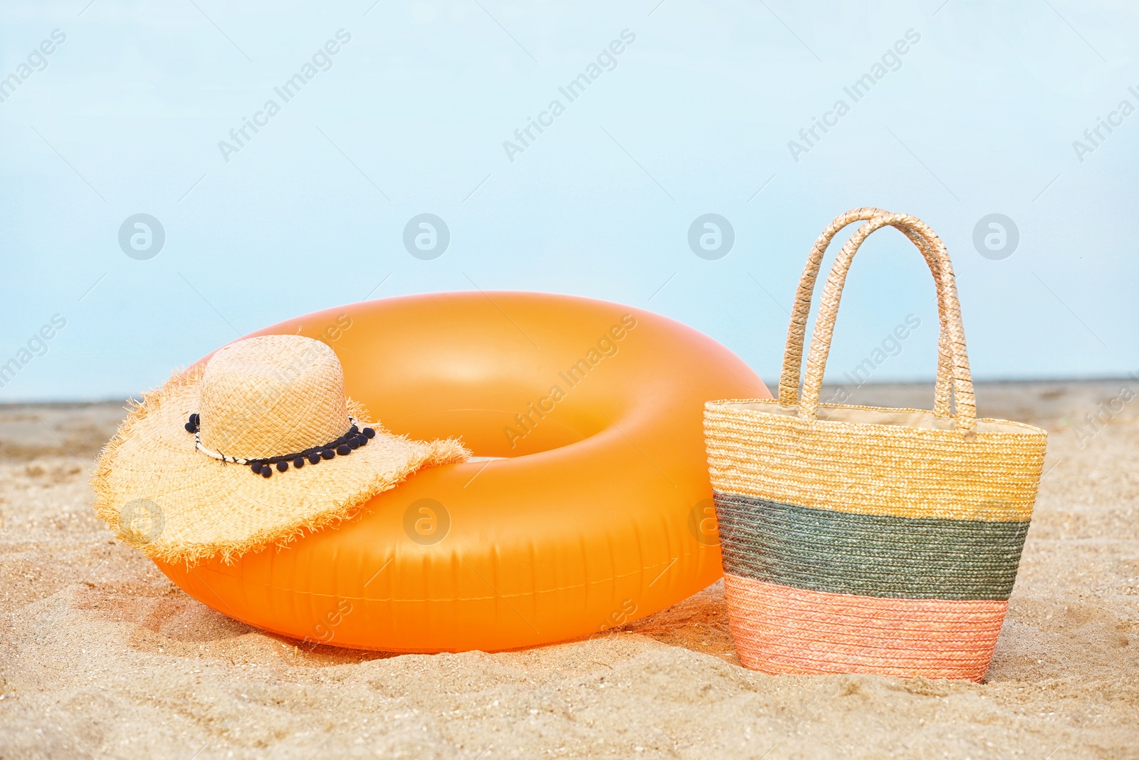 Photo of Colorful inflatable ring, hat and bag on sand. Beach object