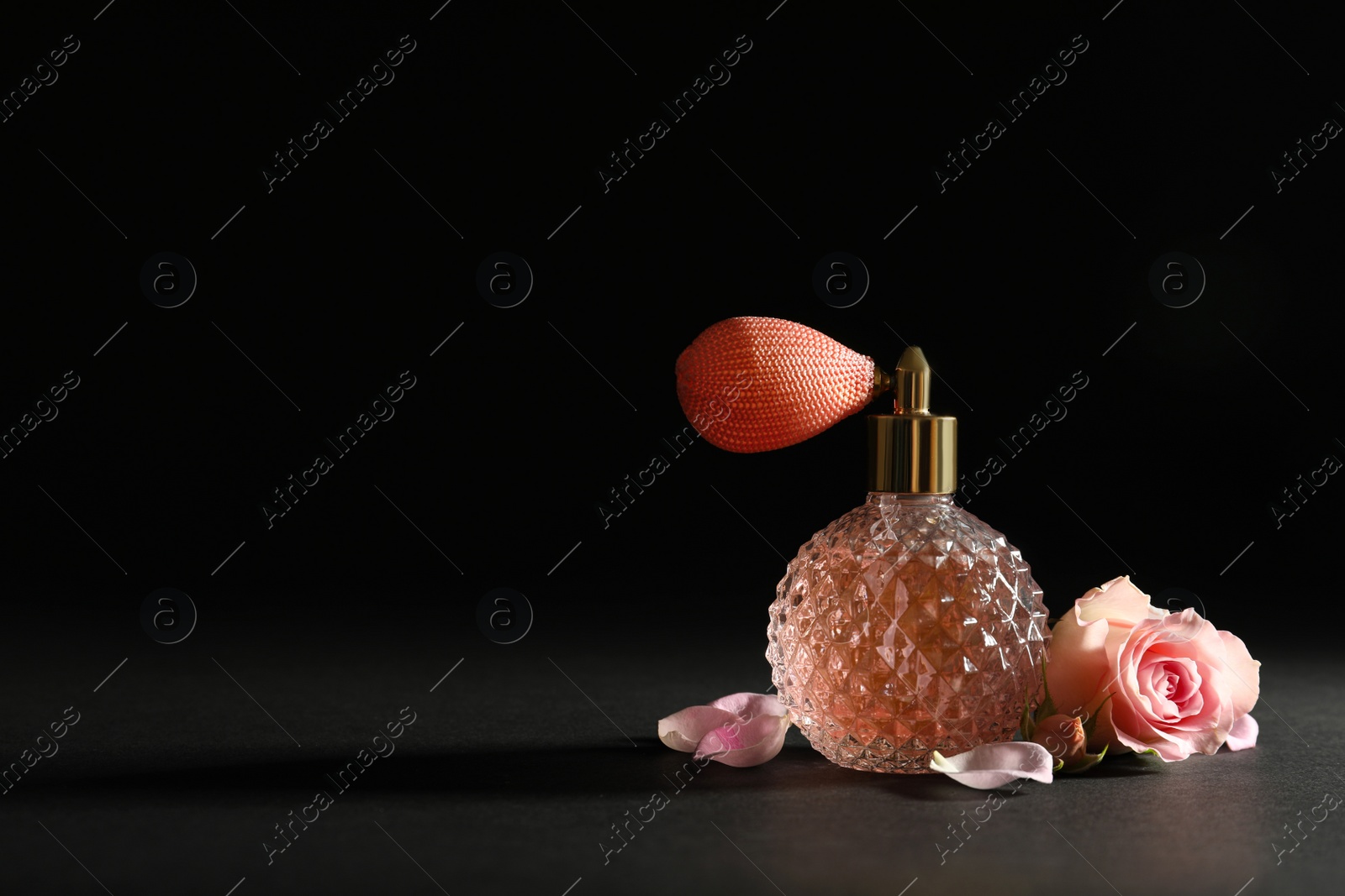 Photo of Vintage bottle of perfume and beautiful flower on black background, space for text