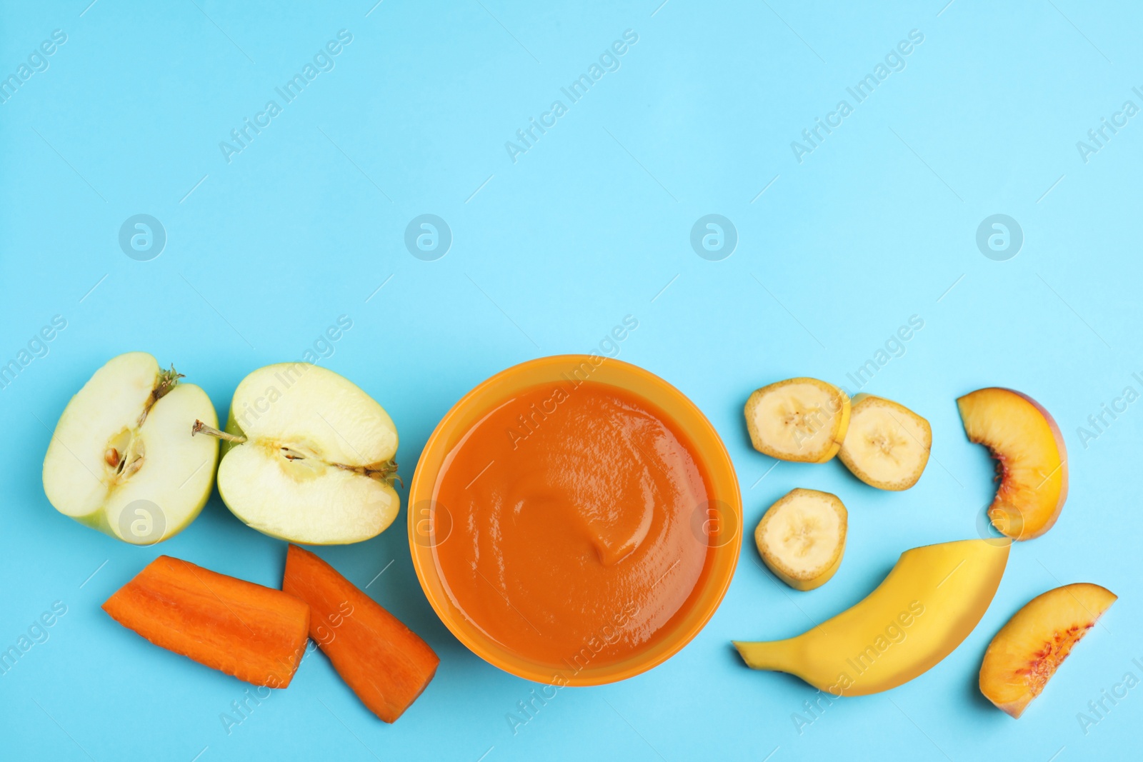 Photo of Baby food in bowl and fresh ingredients on light blue background, flat lay. Space for text