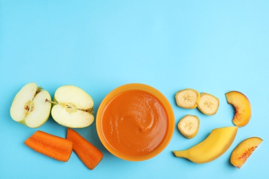 Baby food in bowl and fresh ingredients on light blue background, flat lay. Space for text