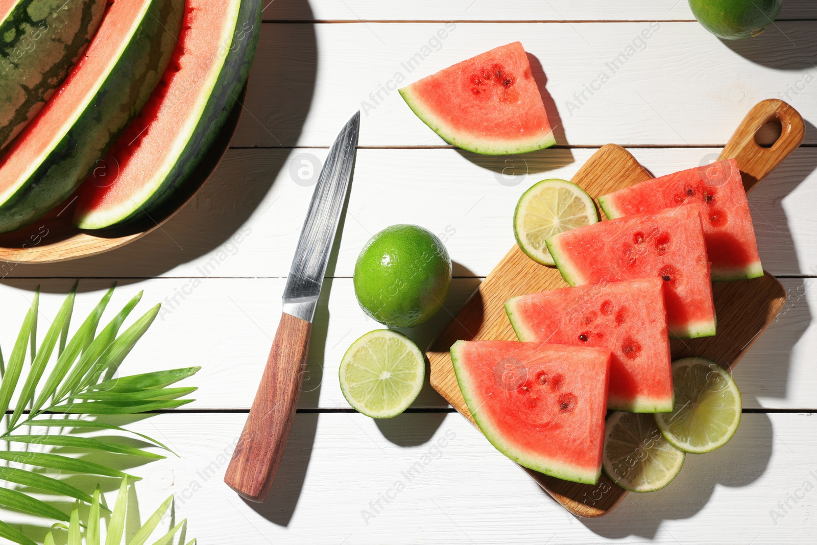 Photo of Tasty sliced watermelon and limes on white wooden table, flat lay