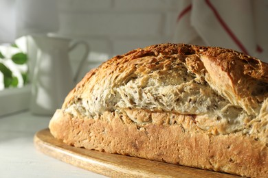 Freshly baked sourdough bread on white wooden table indoors, closeup