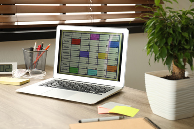 Modern laptop with calendar app at table in office