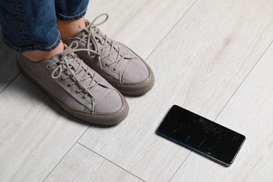 Woman near dropped smartphone on floor, closeup. Device repairing