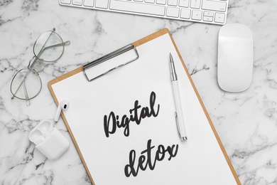 Photo of Flat lay composition of clipboard with phrase DIGITAL DETOX on white marble table