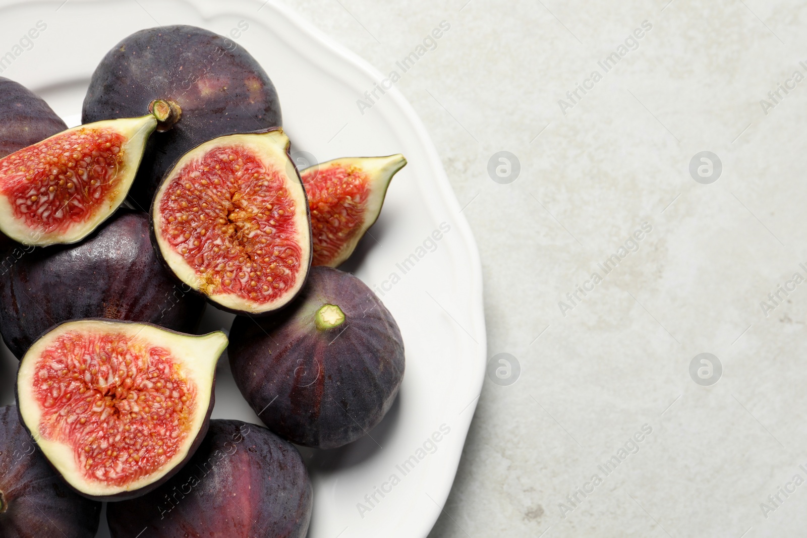 Photo of Whole and cut ripe figs on light table, top view. Space for text