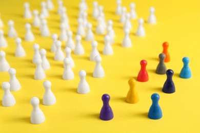 Photo of Colorful pawns on yellow background. Social inclusion concept