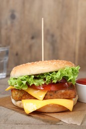 Photo of Delicious burger with tofu, fresh vegetables and sauce on wooden table