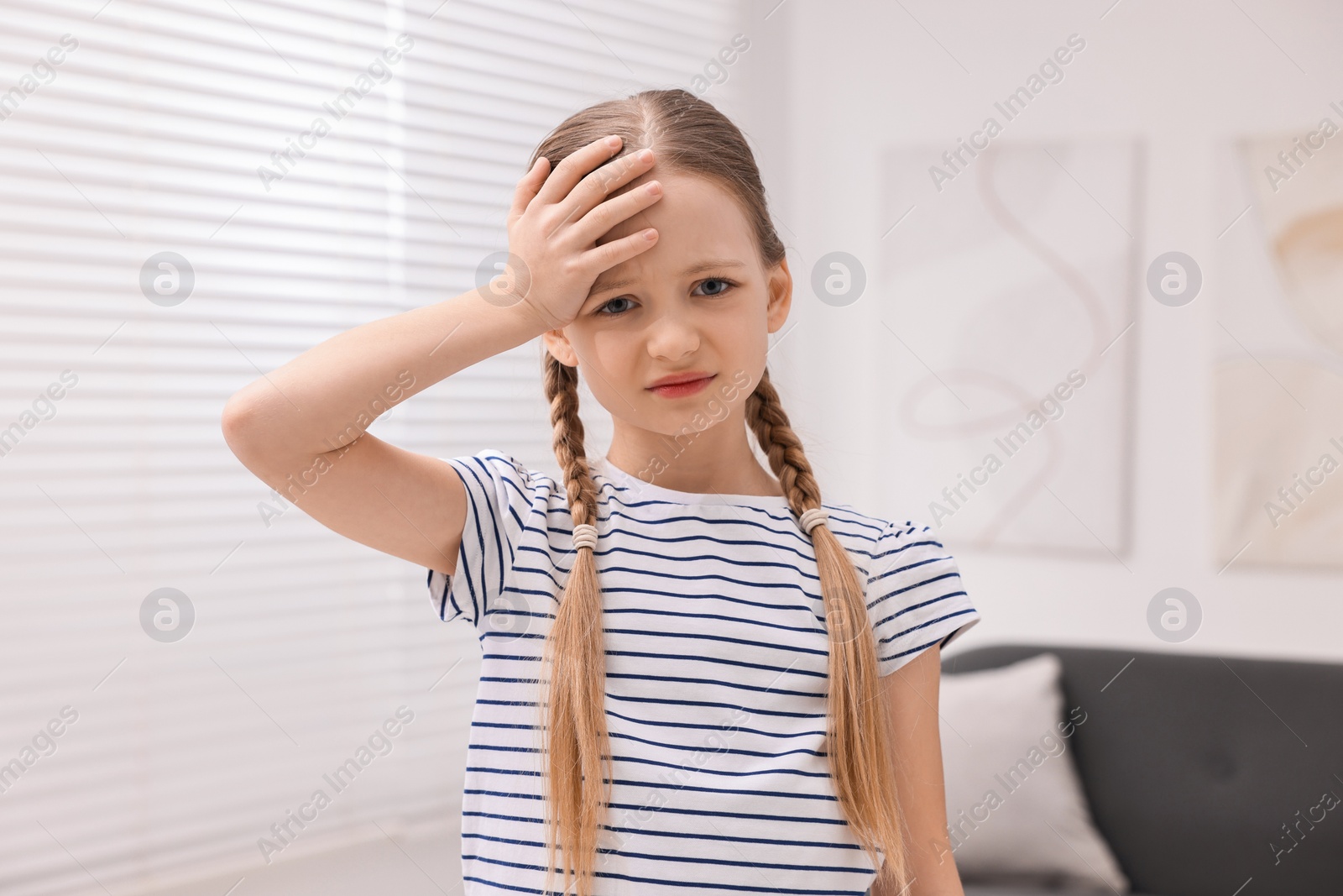 Photo of Little girl suffering from headache at home