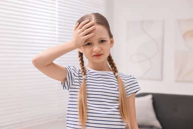 Little girl suffering from headache at home