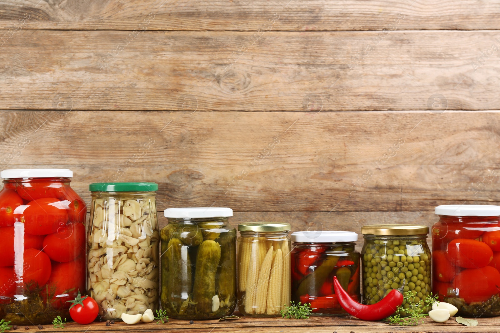 Photo of Jars of pickled vegetables on wooden table