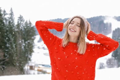 Photo of Happy young woman in warm clothes outdoors. Winter vacation