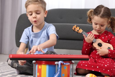 Photo of Little children playing toy musical instruments at home