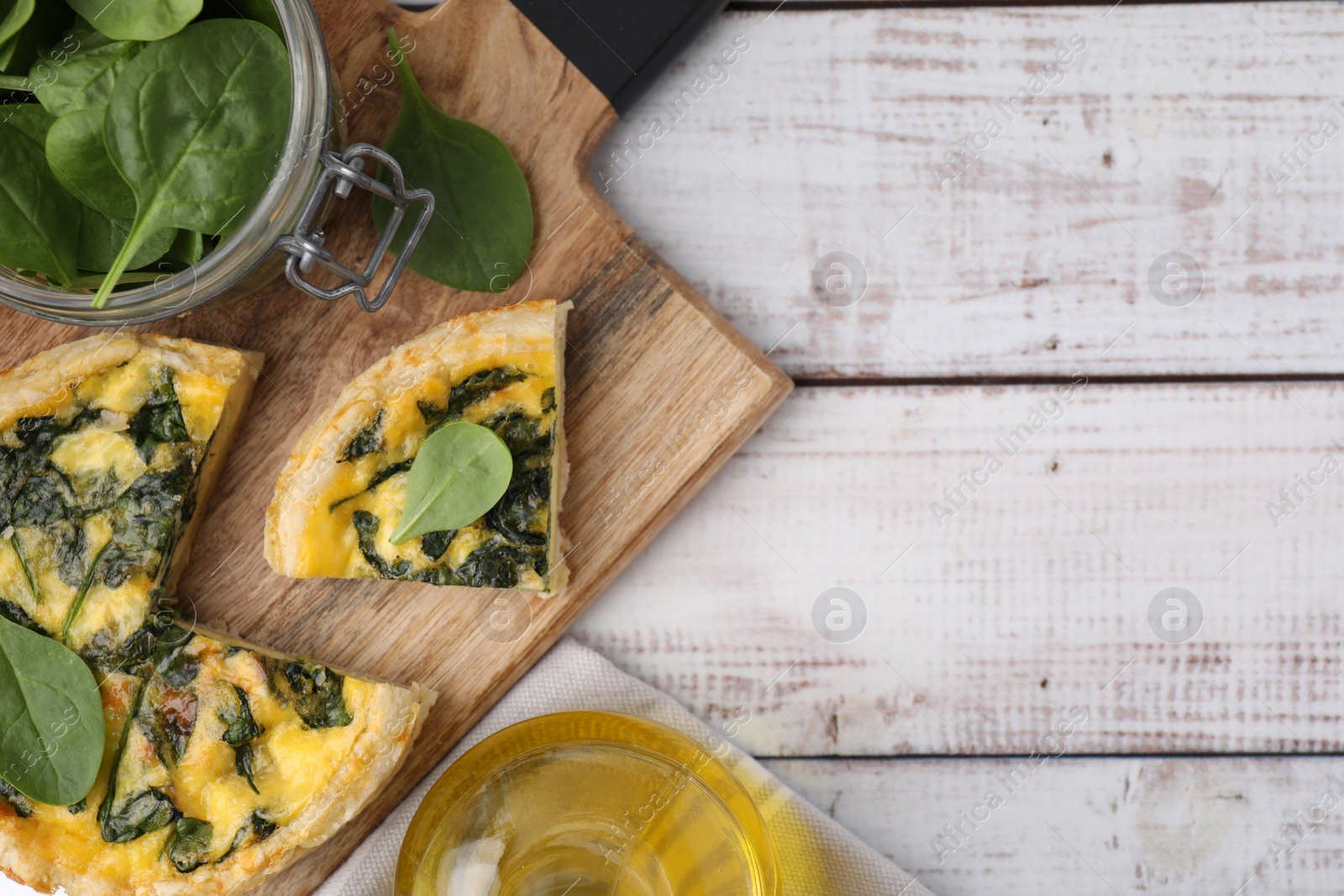 Photo of Delicious cut pie with spinach on white wooden table, top view. Space for text