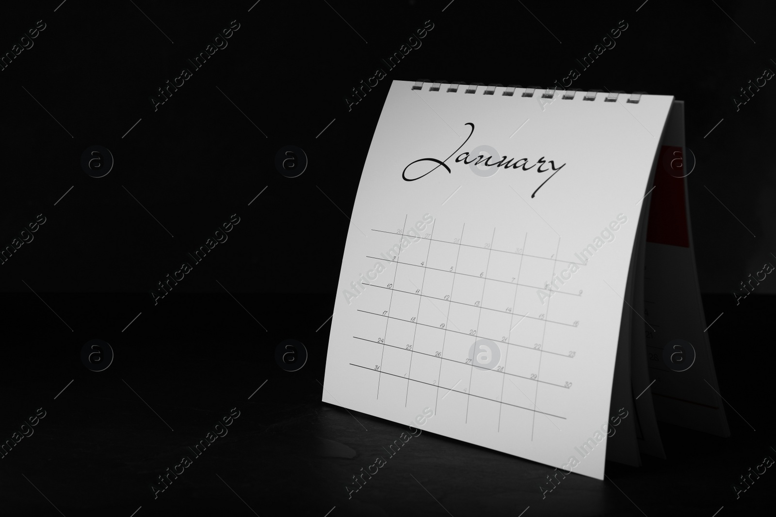 Photo of Paper calendar on black table, space for text. Planning concept