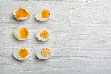 Photo of Various types of boiled eggs on white wooden background, flat lay with space for text. Cooking time