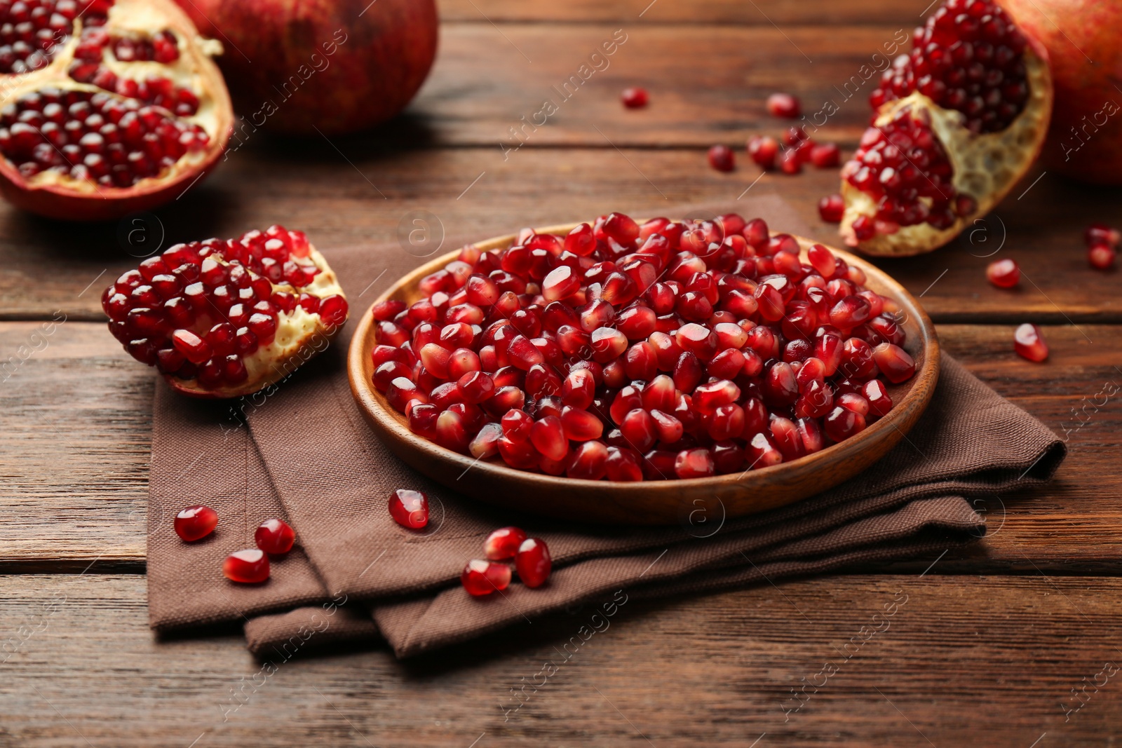 Photo of Ripe juicy pomegranates and grains on wooden table