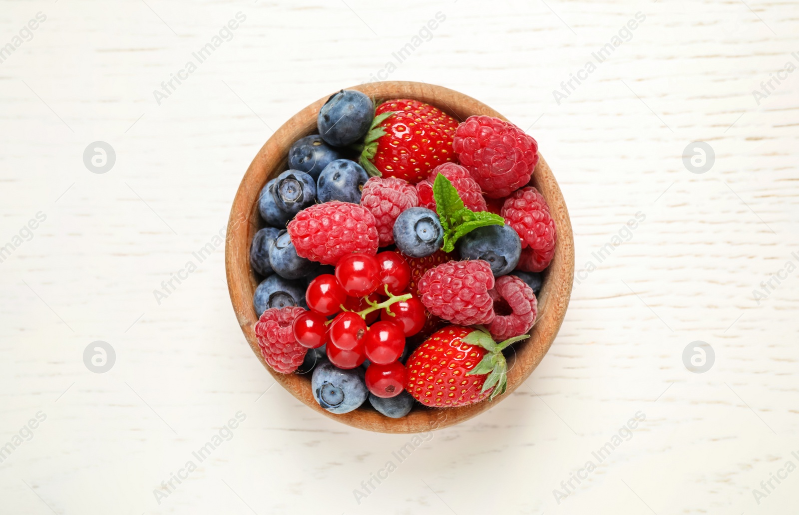 Photo of Mix of different fresh berries in bowl on white wooden table, top view