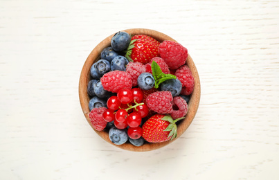 Photo of Mix of different fresh berries in bowl on white wooden table, top view