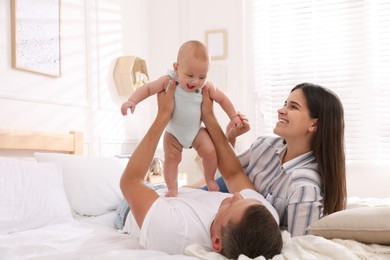 Photo of Happy family with their cute baby on bed at home