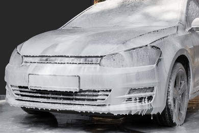 Auto with cleaning foam at outdoor car wash