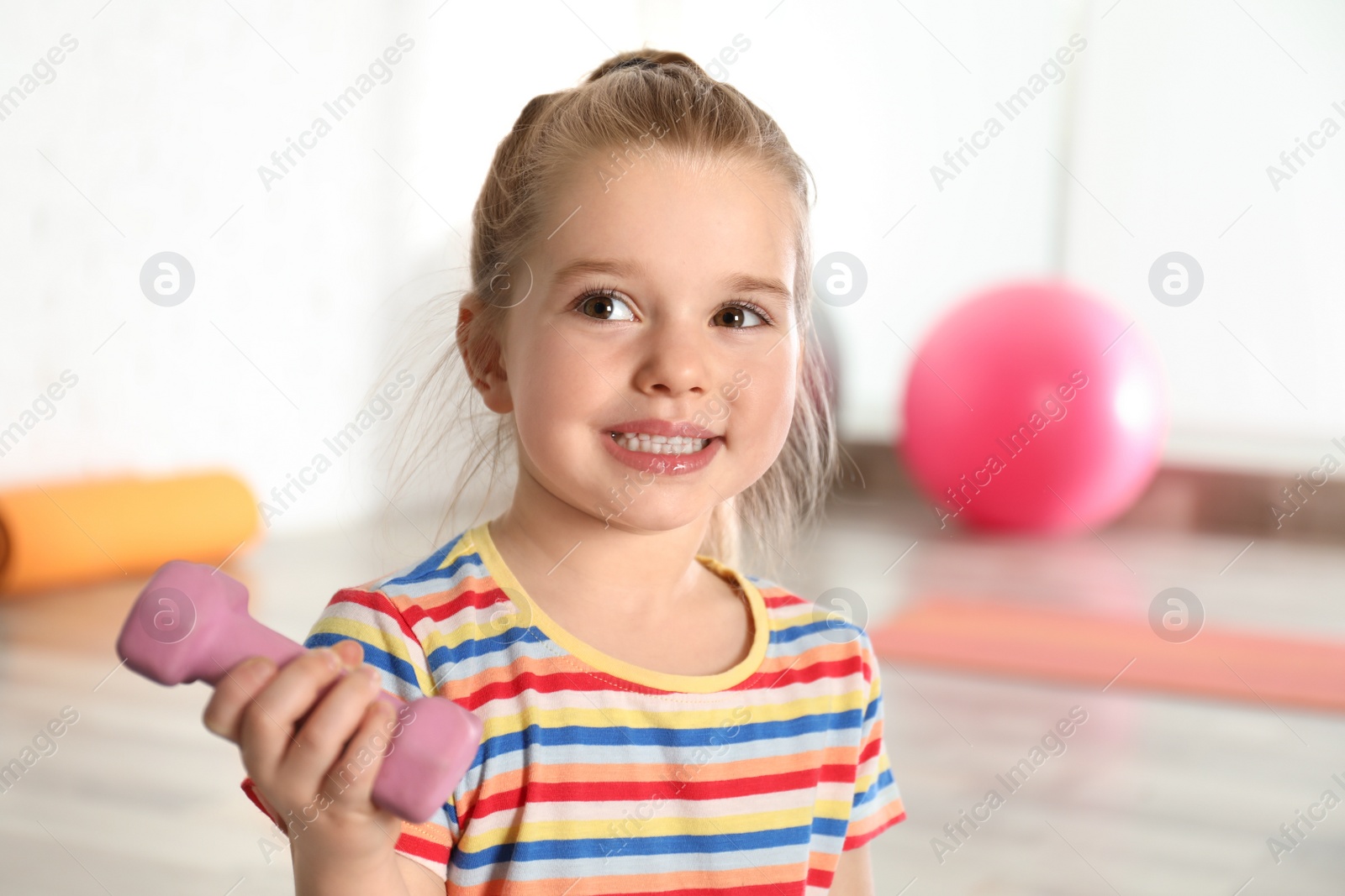 Photo of Little girl with dumbbell in hospital gym. Orthopedist's help