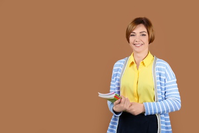 Photo of Portrait of female teacher with notebooks on color background