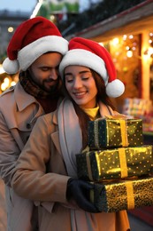 Photo of Lovely couple with Christmas presents at winter fair