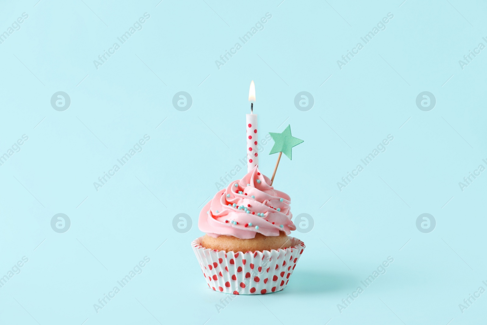 Photo of Birthday cupcake with burning candle and topper on light blue background
