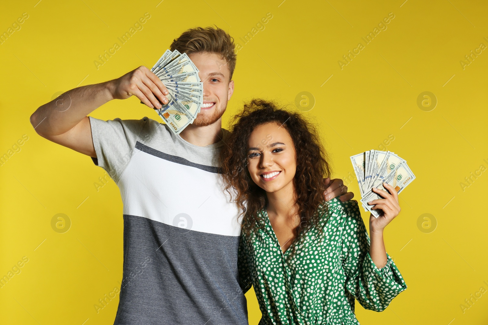 Photo of Young couple with money on color background