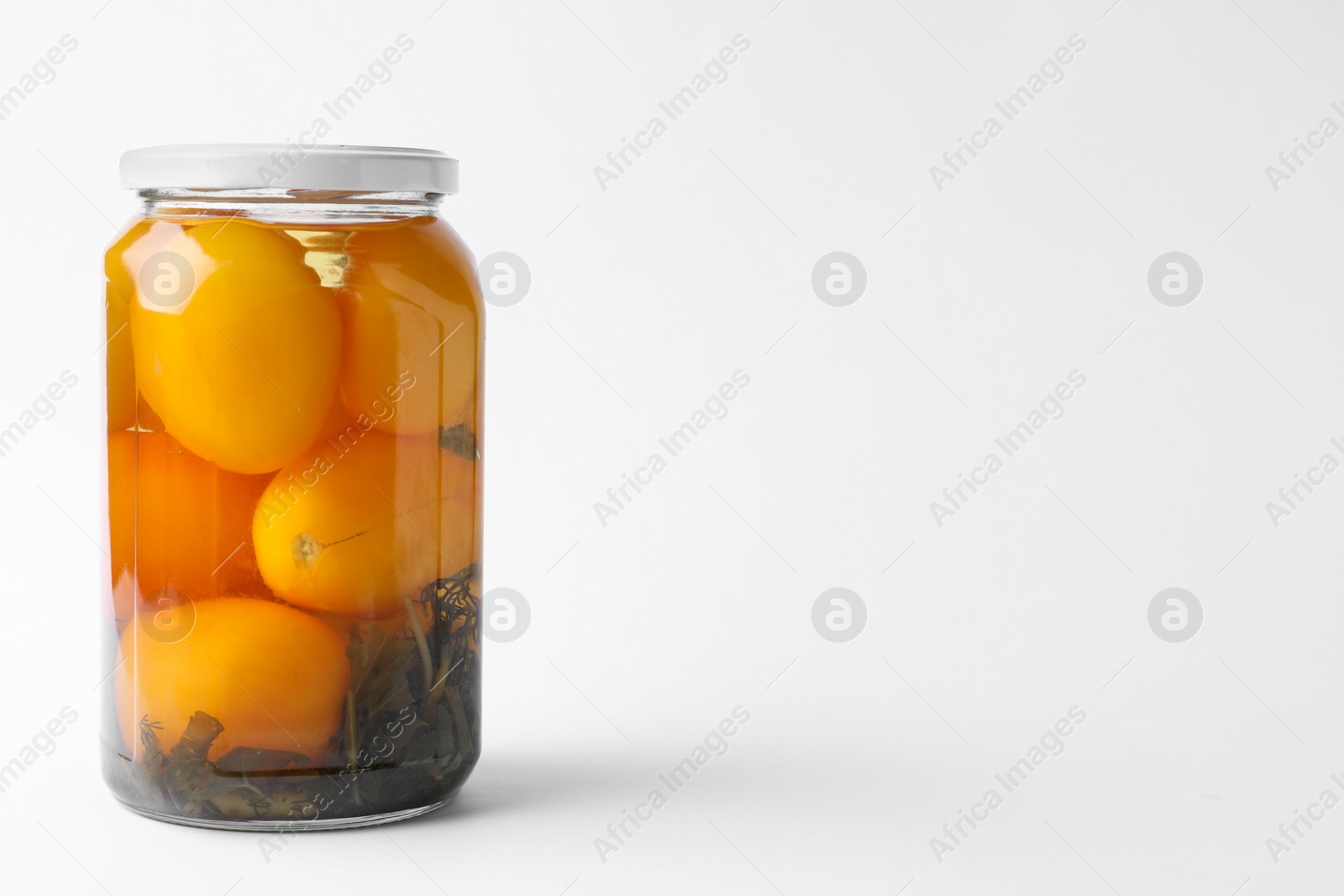 Photo of Jar of pickled yellow tomatoes on white background