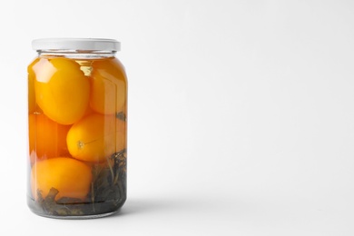 Jar of pickled yellow tomatoes on white background