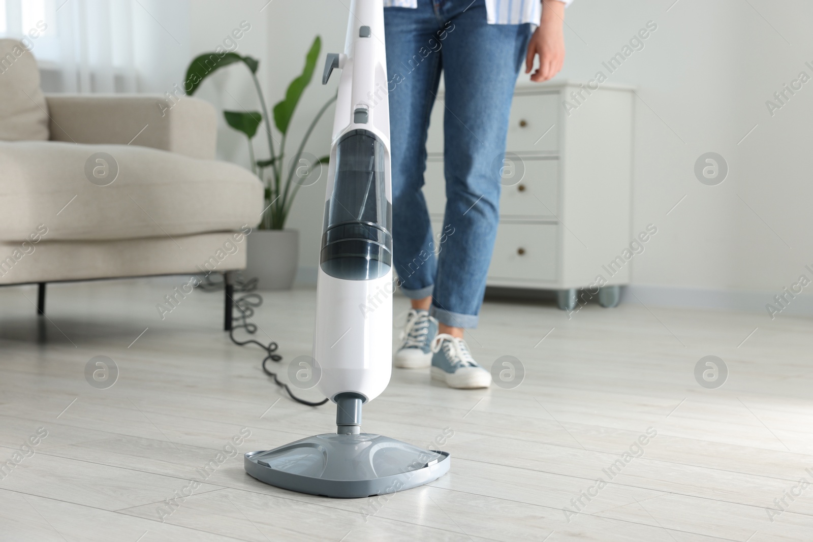 Photo of Woman cleaning floor with steam mop at home, closeup