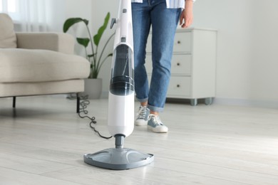 Woman cleaning floor with steam mop at home, closeup