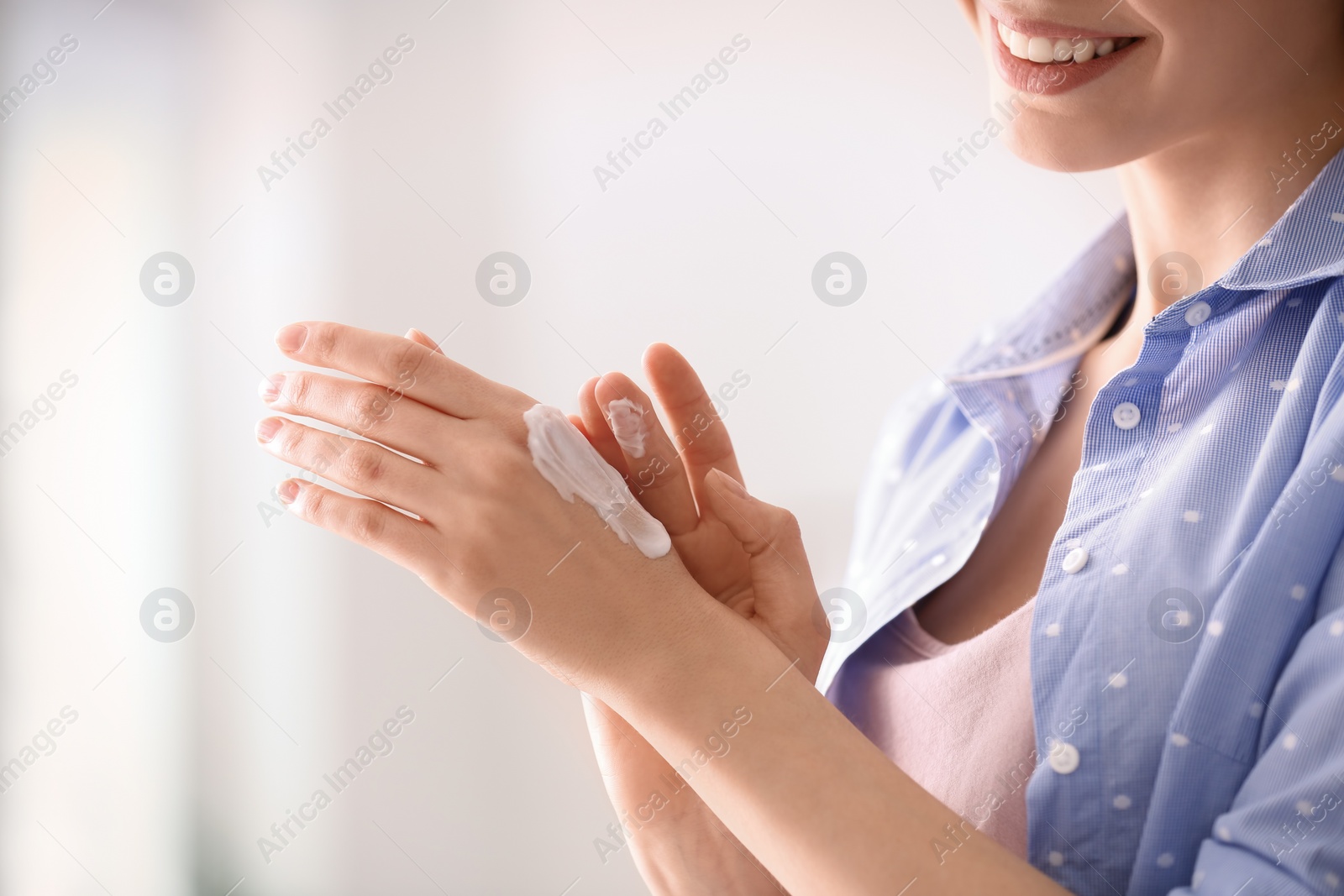 Photo of Young woman applying hand cream at home, closeup