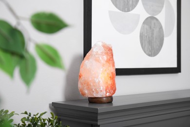 Photo of Himalayan salt lamp on grey console table near wall in room