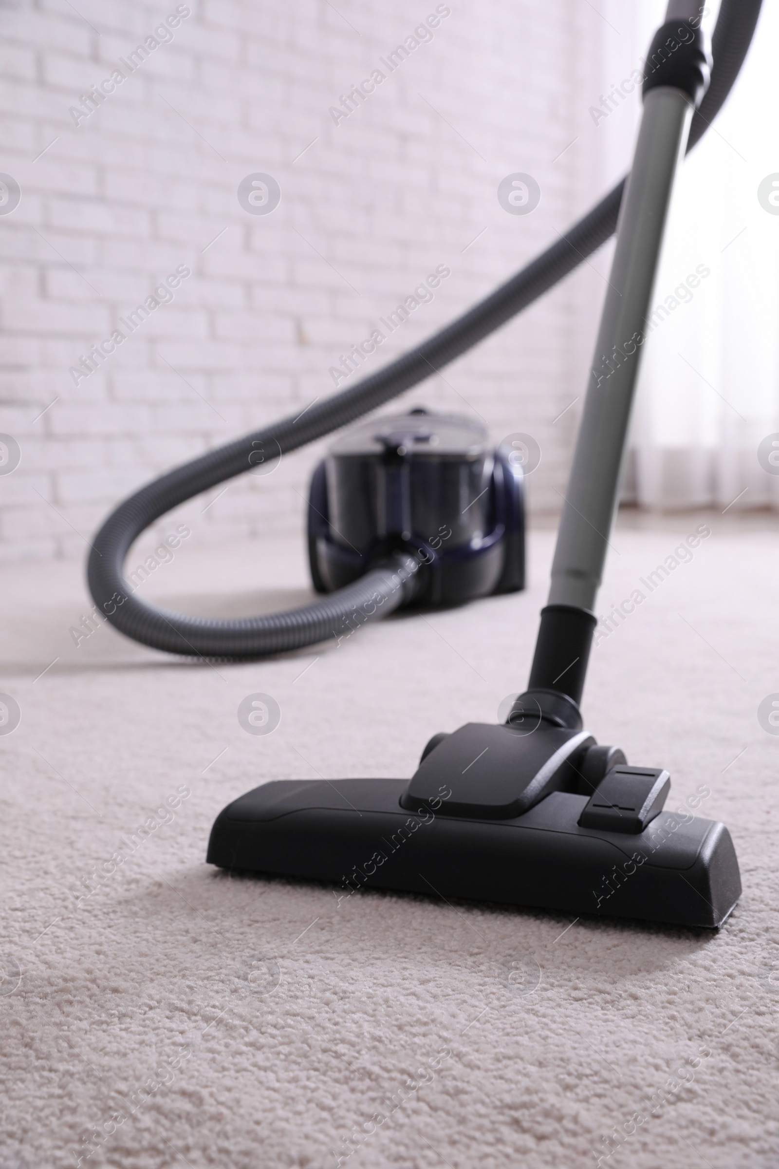 Photo of Modern vacuum cleaner on carpet in room