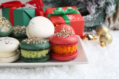 Photo of Beautifully decorated Christmas macarons, gift boxes and festive decor on snow, closeup